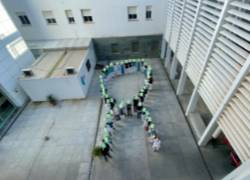 Lazo verde formado por trabajadores por Día Mundial del Cáncer