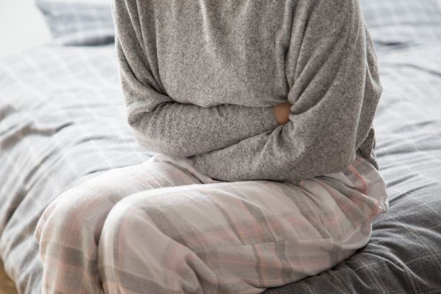 okmujer-enferma-cama-manteniendo-manos-estomago-sufriendo-dolor