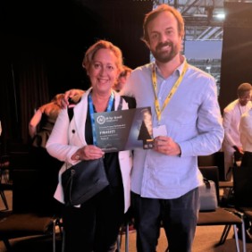 La Dra. Sara Heili y Daniel Oliva sostienen el diploma de finalista en el AI for Good Global Summit 2026 para Emily.AI
