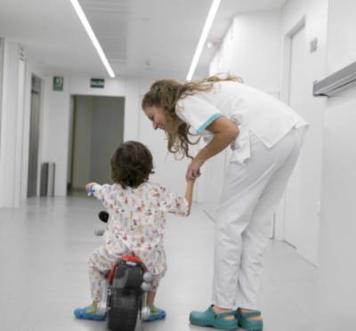 Niño hospitalizado con minimoto y enfermera de Quirónsalud