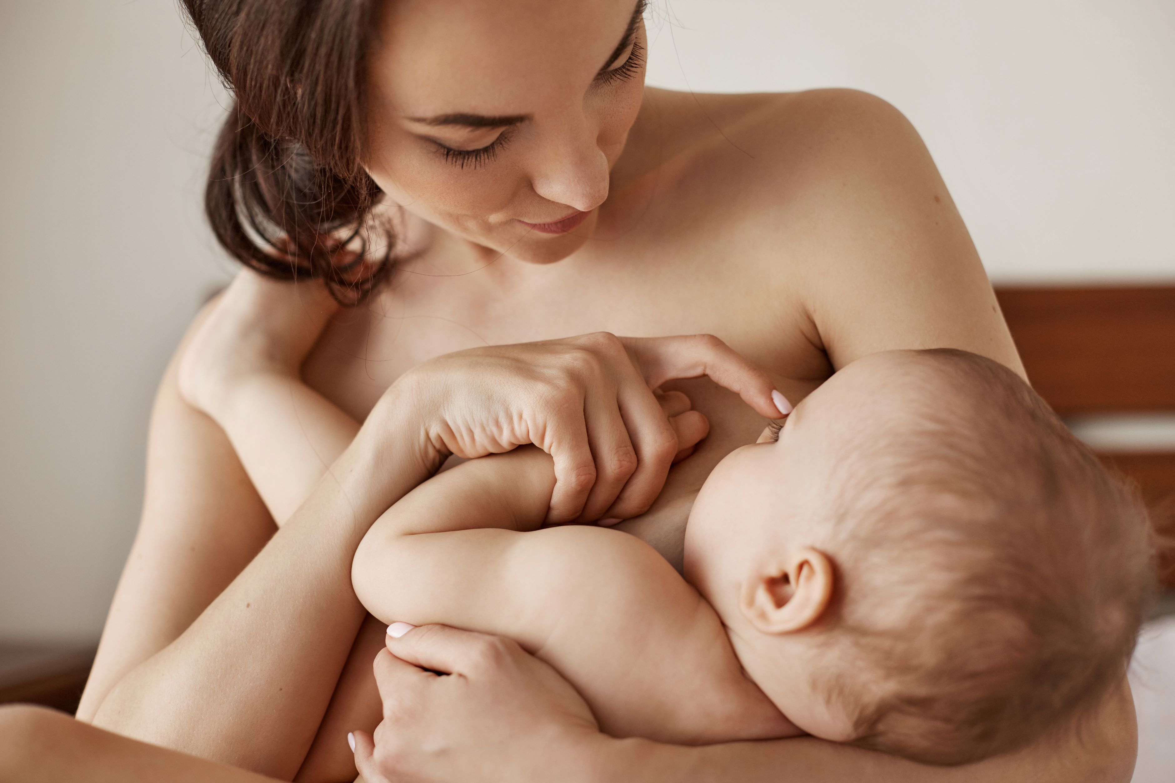 okok young-tender-nude-mother-breastfeeding-hugging-her-newborn-baby-sitting-bed-morning